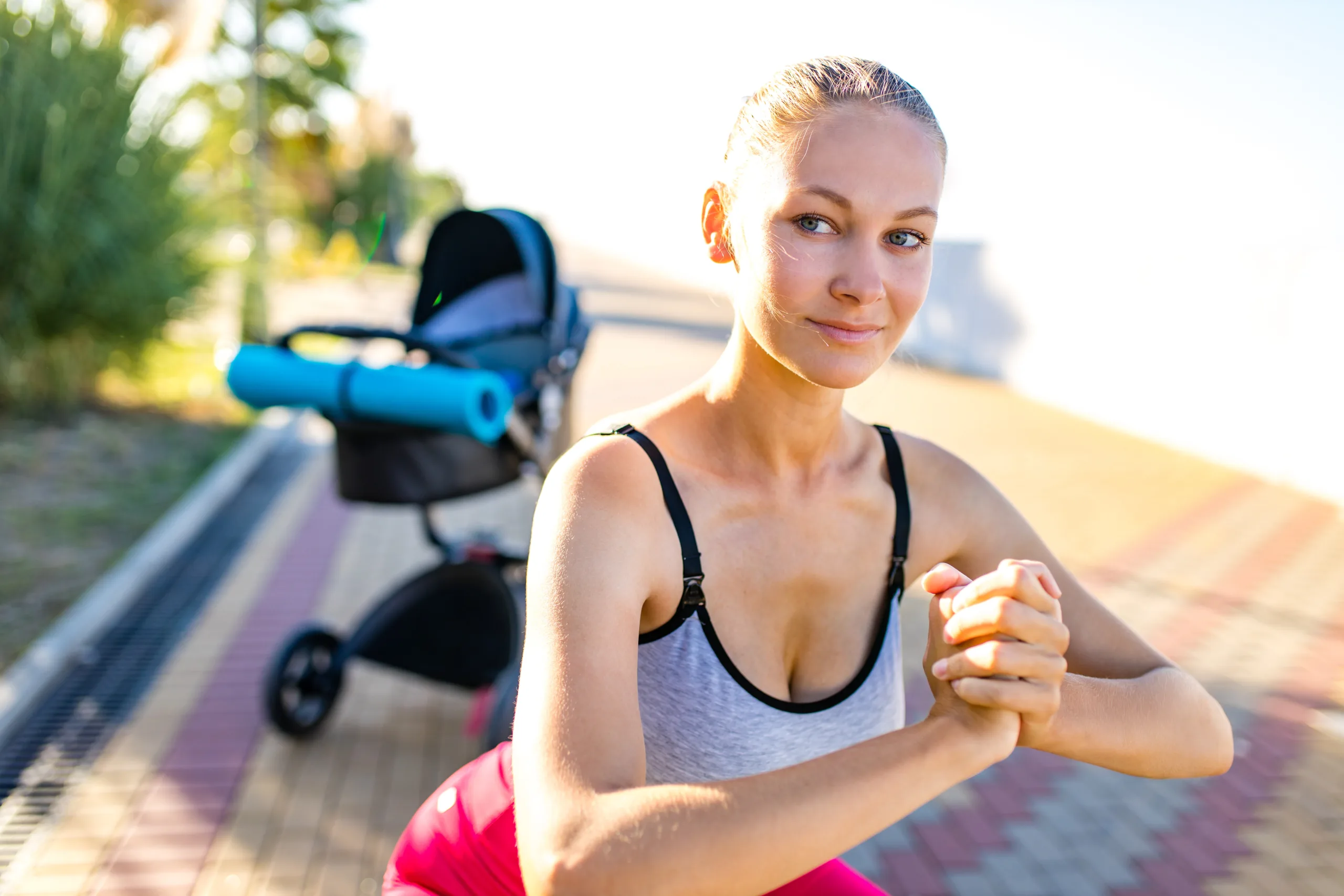 blonde woman training gymnastic with newborn kid on freah air in tropical sunny beach